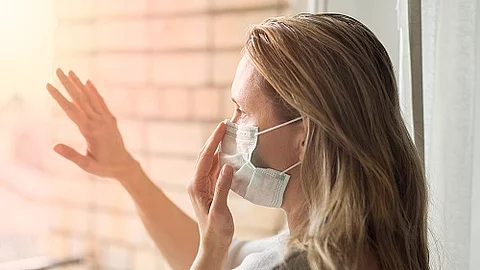 Social-Dinstancing, Frau mit Maske am Fenster