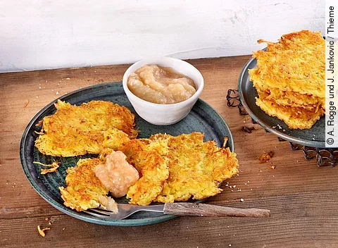 Kartoffelpuffer mit Apfelmus arrangiert auf einem Teller auf Holztisch