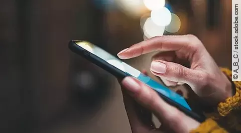 Hand schreibt etwas auf dem Smartphone