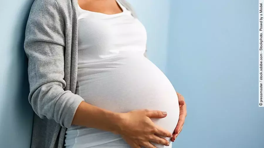 Schwangere Frau hält sich mit ihren Händen den Bauch