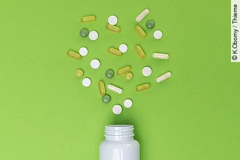 Verschiedene, verstreute Medikamente auf grünem Hintergrund. 