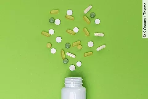 Verschiedene, verstreute Medikamente auf grünem Hintergrund. 