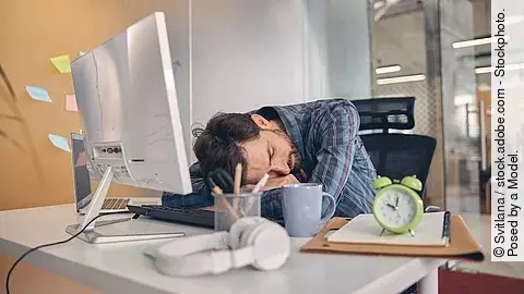 Junger Mann macht ein Power-Nap mit Kopf auf dem Schreibtisch