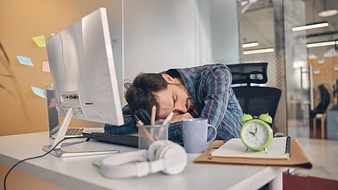 Junger Mann macht ein Power-Nap mit Kopf auf dem Schreibtisch Junger Mann macht ein Power-Nap mit Kopf auf dem Schreibtisch