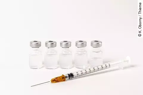 5 Ampullen mit Impfserum und 1 Spritze vor weißem Hintergrund