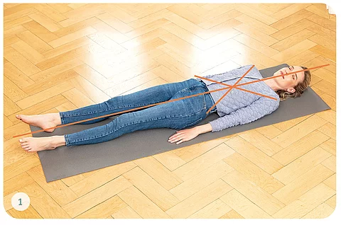 Junge Frau in Alltagskleidung macht Übungen auf Yogamatte 