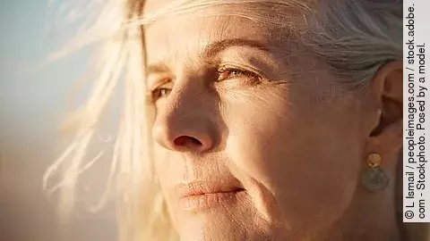 50+ Frau blickt nachdenklich in die Ferne