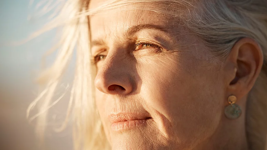 50+ Frau blickt nachdenklich in die Ferne