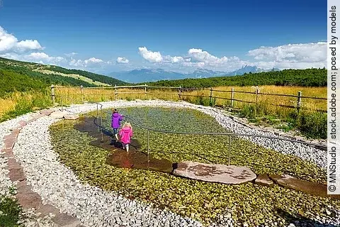 Zwei Kinder beim Wassertreten in Berglandschaft