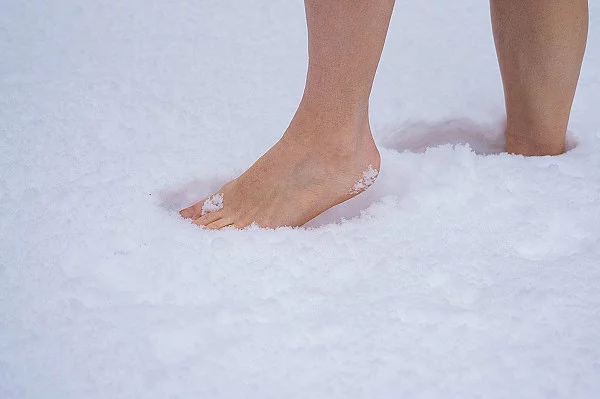 Close-up von den Füßen einer Frau, die durch den Schnee geht.