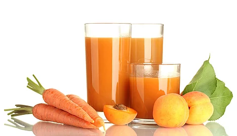 2 Gläser mit Möhrensaft, arrangiert mit frischen Möhren und Aprikosen
