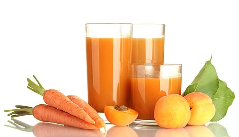 2 Gläser mit Möhrensaft, arrangiert mit frischen Möhren und Aprikosen