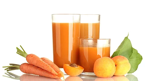 2 Gläser mit Möhrensaft, arrangiert mit frischen Möhren und Aprikosen