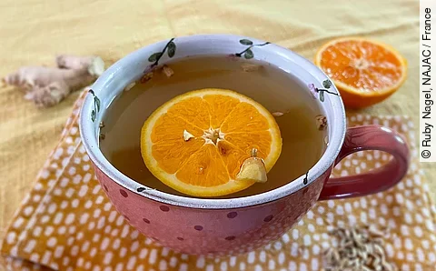 Eine Tasse Tee mit Orangenscheibe darin.