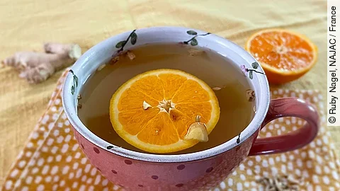 Eine Tasse Tee mit Orangenscheibe darin.