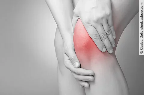 Schmerzende Knie in schwarz/weiß. Das Knie ist rot gefärbt.