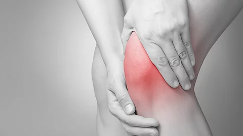Schmerzende Knie in schwarz/weiß. Das Knie ist rot gefärbt.