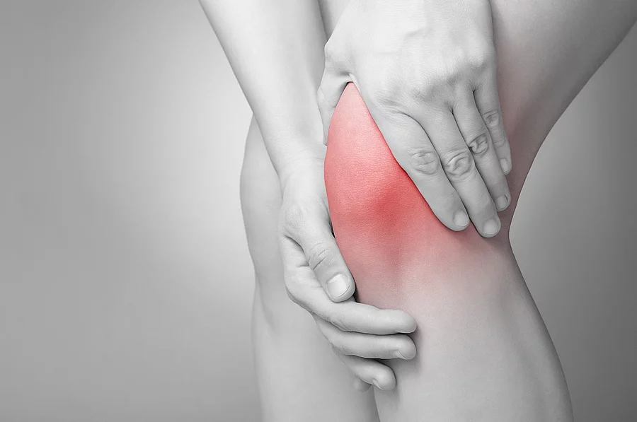Schmerzende Knie in schwarz/weiß. Das Knie ist rot gefärbt.