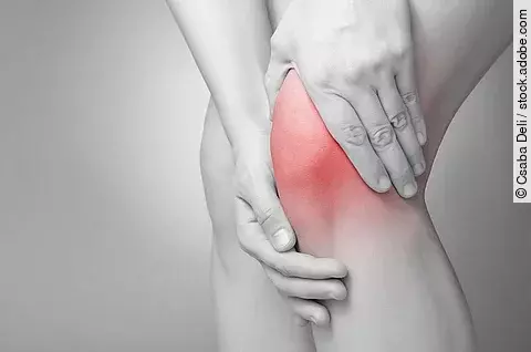 Schmerzende Knie in schwarz/weiß. Das Knie ist rot gefärbt.