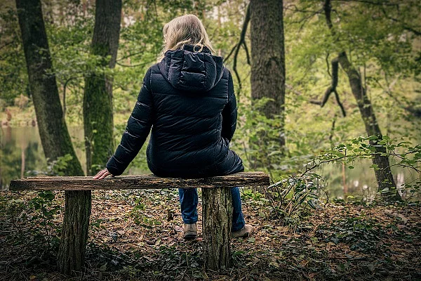 Frau sitzt auf einer Parkbank im Herbst.