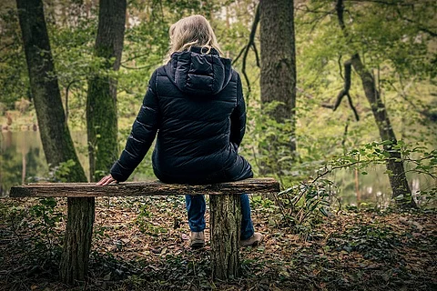 Frau sitzt auf einer Parkbank im Herbst.