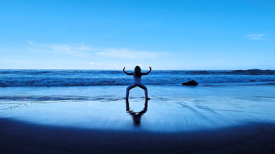 Qigong Frau (von hinten zu sehen) macht Qigong am Meer