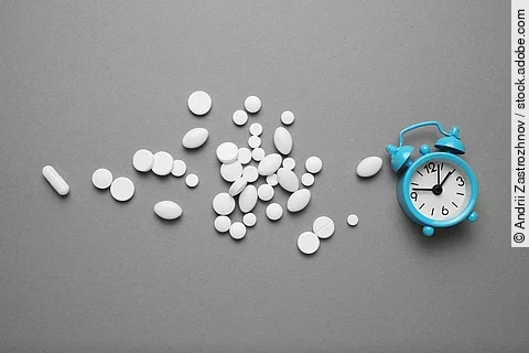 weiße Pillen und ein Wecker