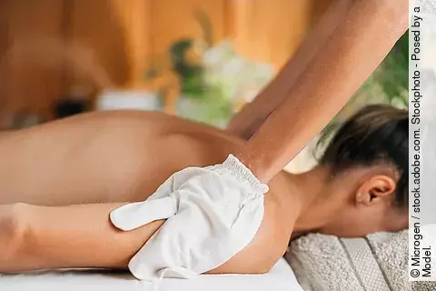 Frau liegt auf dem Bauch auf Massageliege, ayurvedische Ölmassage