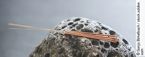 Nahaufnahme: Akupunkturnadeln auf Lavastein