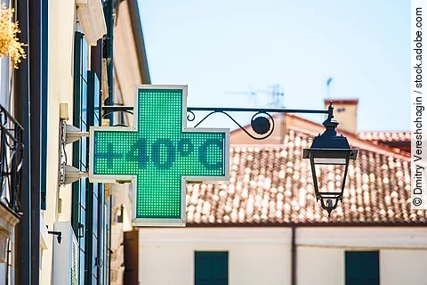 An einem Sommertag zeigt ein Thermometer auf der Straße in Form eines grünen Kreuzes eine Teperatur von 40 Grad Celsius an. 