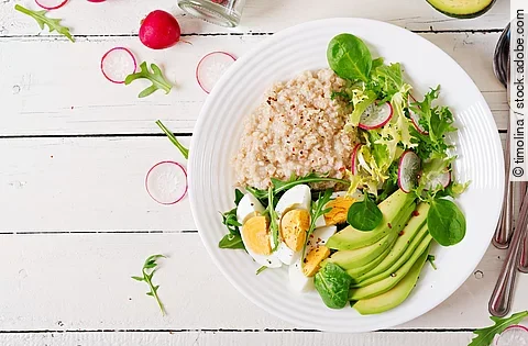 Haferporridge mit Avocado, Ei und Radieschen auf einem Teller angerichtet