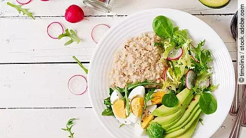 Haferporridge mit Avocado, Ei und Radieschen auf einem Teller angerichtet