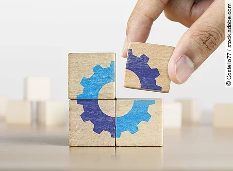 Ein letztes Puzzlestück in Form von einem Holzklotz wird zusammengefügt.