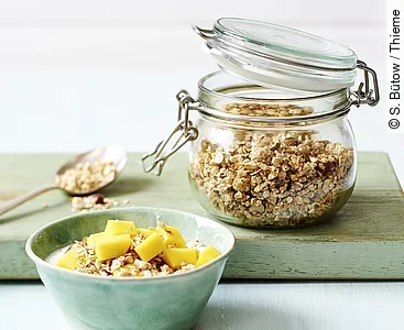 Vorratsglas mit Müsli, eine Schale mit Müsli und frischen Früchten