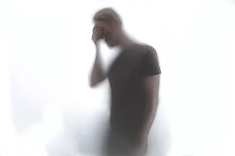 Silhouette eines Mannes, der sich an die Stirn fasst.