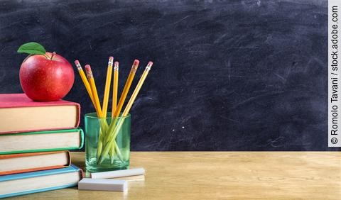 Bücherstapel, Stiftebecher und Apfel auf einem Schreibtisch; Symbolbild für Bildung