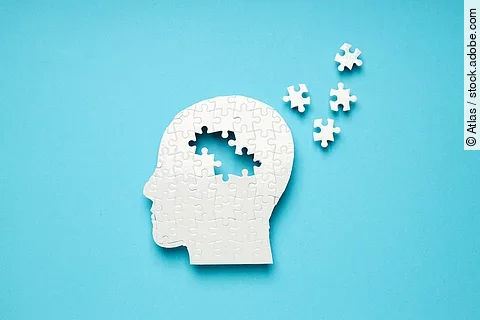 Symbolbild Alzheimer: Weißes Puzzle eines Kopfes, aus dem sich Puzzle-Teile lösen 