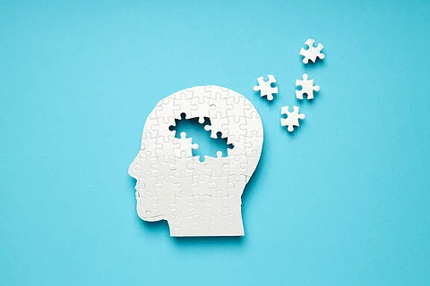 Symbolbild Alzheimer: Weißes Puzzle eines Kopfes, aus dem sich Puzzle-Teile lösen 