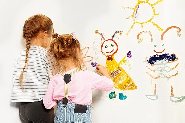 Zwei kleine Mädchen zeichnen auf einen weißen Hintergrund. 