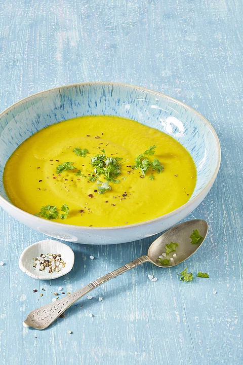 Suppe in blauer Schale serviert mit Petersilie.