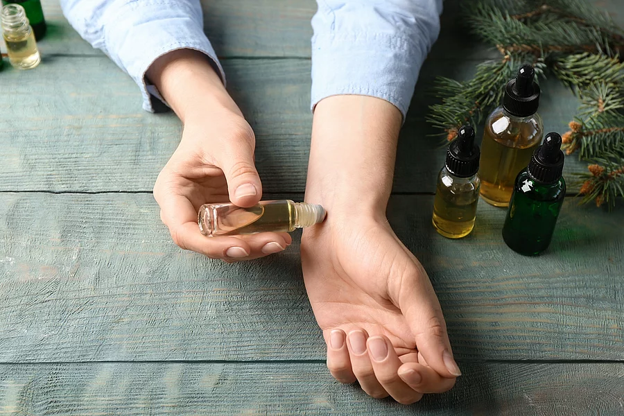 Frau trägt Aromaöl auf dem Handgelenk auf.