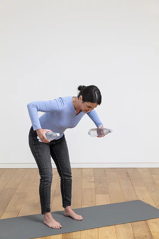 Frau mach Übungen mit Wasserflaschen auf Yogamatte