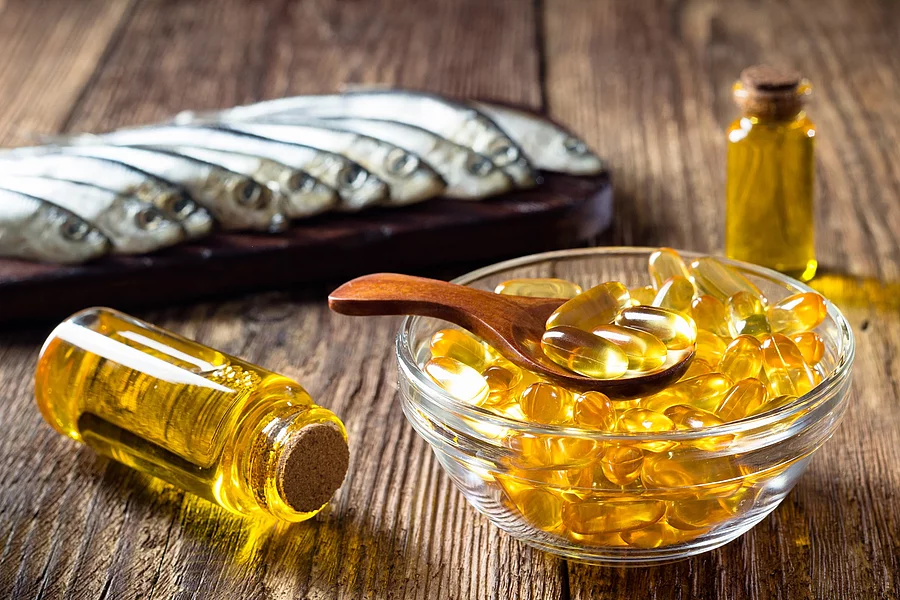 Fischölkapseln, Sardinen und Vitamin-D-Öl in einem Fläschchen auf einem Holztisch arrangiert 