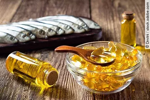 Fischölkapseln, Sardinen und Vitamin-D-Öl in einem Fläschchen auf einem Holztisch arrangiert 
