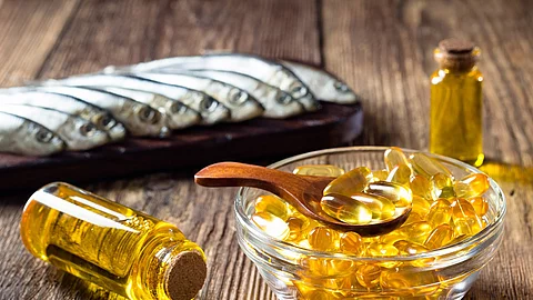 Fischölkapseln, Sardinen und Vitamin-D-Öl in einem Fläschchen auf einem Holztisch arrangiert 