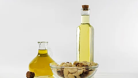 Beispiele für gesunde Fette: Pflanzenöle in Flaschen, eine Schale mit Nüssen