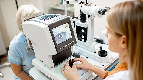 Augenärztin kontrolliert das Auge einer Patientin durch ein Messgerät.