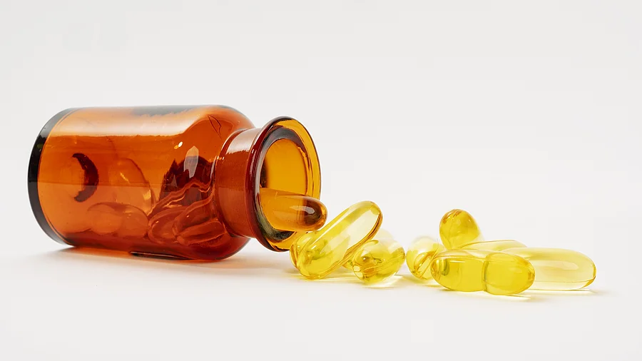 liegendes Braunfläschchen mit gelben Omega-3-Kapseln