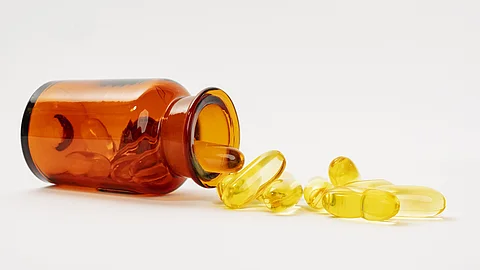 liegendes Braunfläschchen mit gelben Omega-3-Kapseln