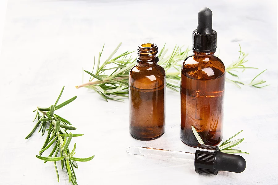 Aromatherapie Symbolbild: Rosmarinzweige und Braunfläschchen